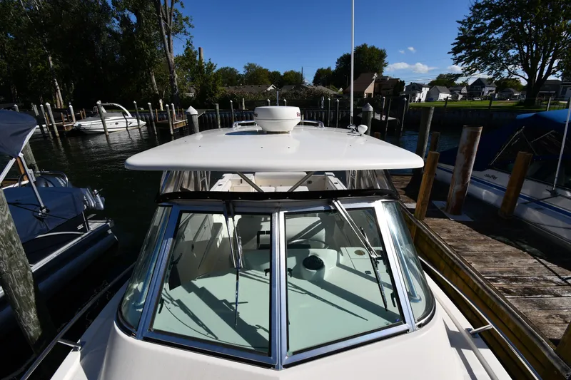 Slide: The Image of 2004 Pursuit 2670 Denali LS boat docked at a marina under clear blue skies. - 6