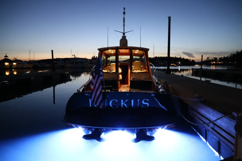 Slide: The Image of Hinckley Talaria 44 yacht at dusk, illuminated with underwater lights, docked in a serene marina. - 2