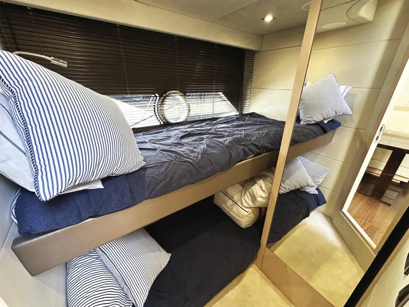 Slide: The Image of Bunk beds in 2015 Sunseeker Predator 57 yacht cabin with striped bedding and porthole window. - 35