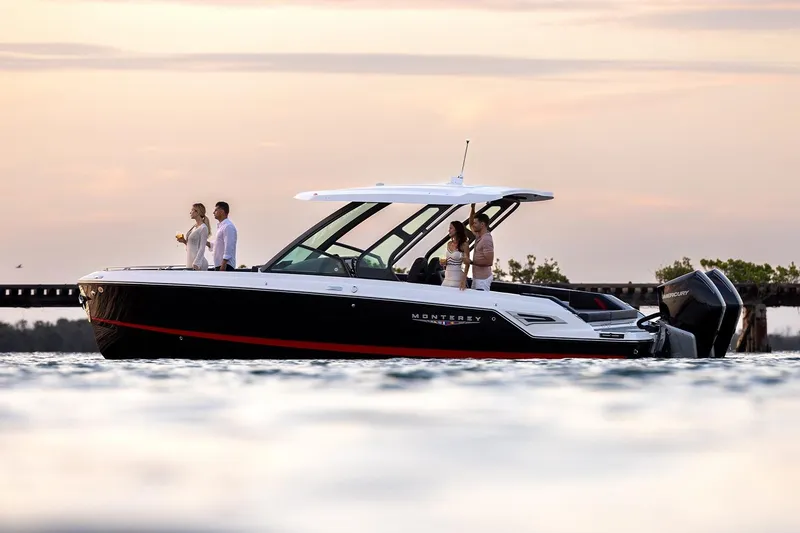 Slide: The Image of 2027 Monterey Elite 30 OB boat on water at sunset with passengers enjoying the view. - 2