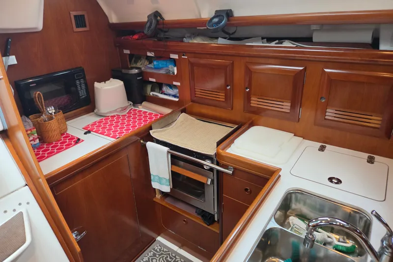 Slide: The Image of Galley kitchen in 2004 Beneteau Oceanis 393 sailboat with wooden cabinetry and modern appliances. - 14