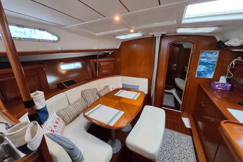 Slide: The Image of Interior of 2004 Beneteau Oceanis 393 sailboat with cozy dining area and wooden finishes. - 13