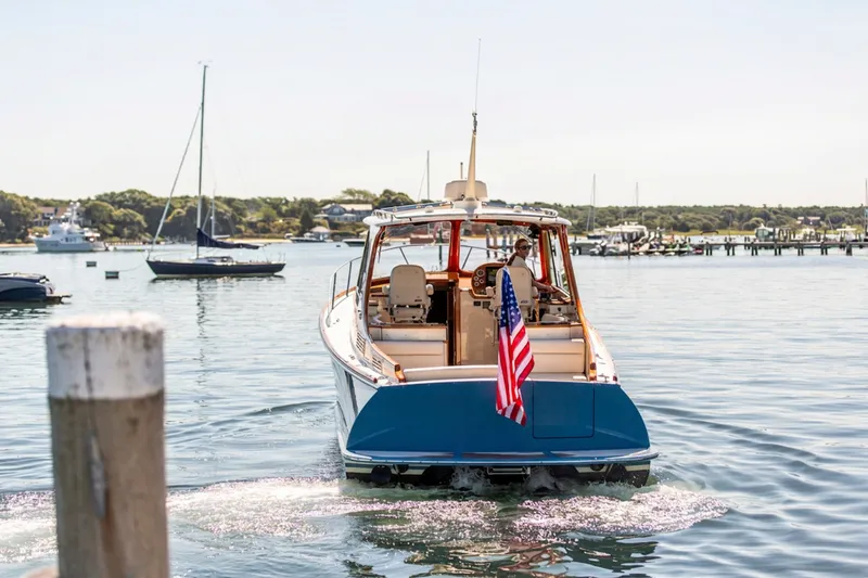 Slide: The Image of 2017 Hinckley Picnic Boat 37 MKIII cruising in a scenic harbor with American flag. - 21