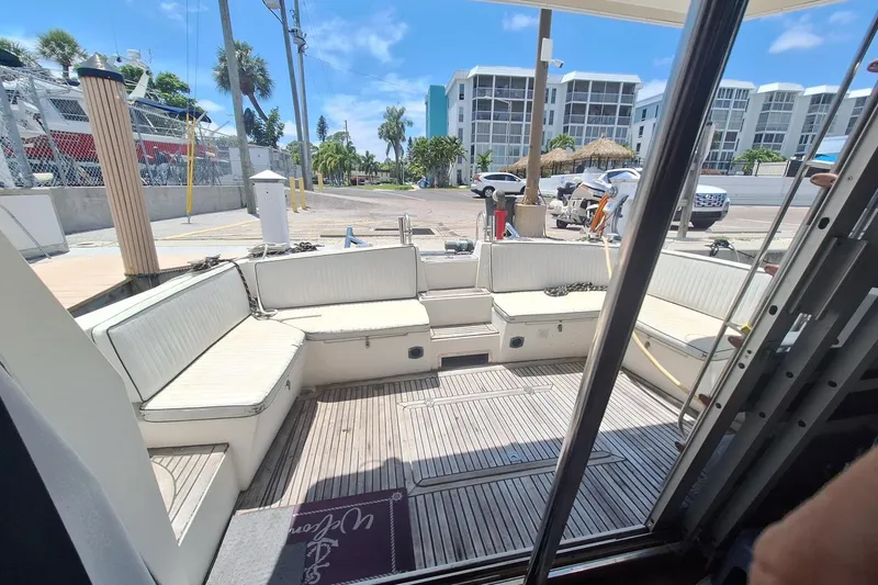 Slide: The Image of 1988 Birchwood 44TS yacht interior with white seating, docked at a marina under clear skies. - 24