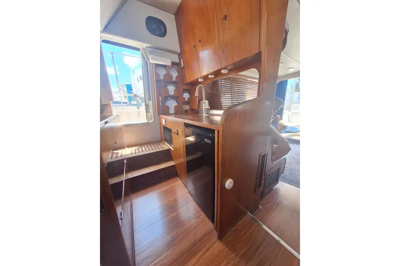 Slide: The Image of Interior of 1988 Birchwood 44TS boat with wooden cabinetry and compact kitchen area. - 19