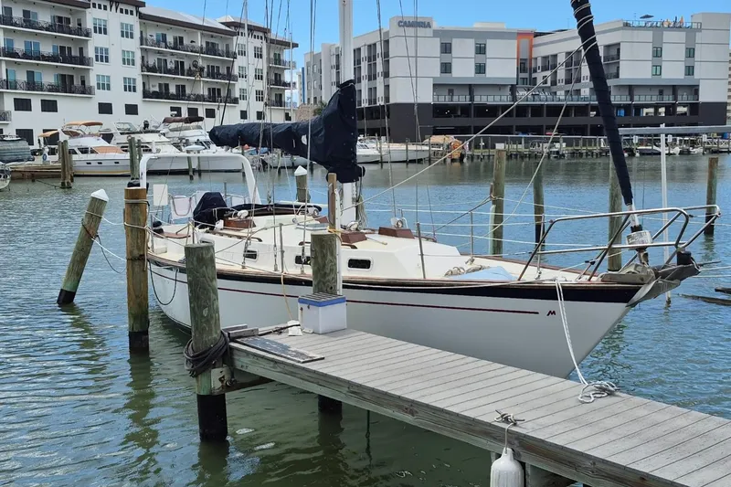 Slide: The Image of 1987 Morgan 384 sailboat docked in marina, surrounded by modern buildings. - 1