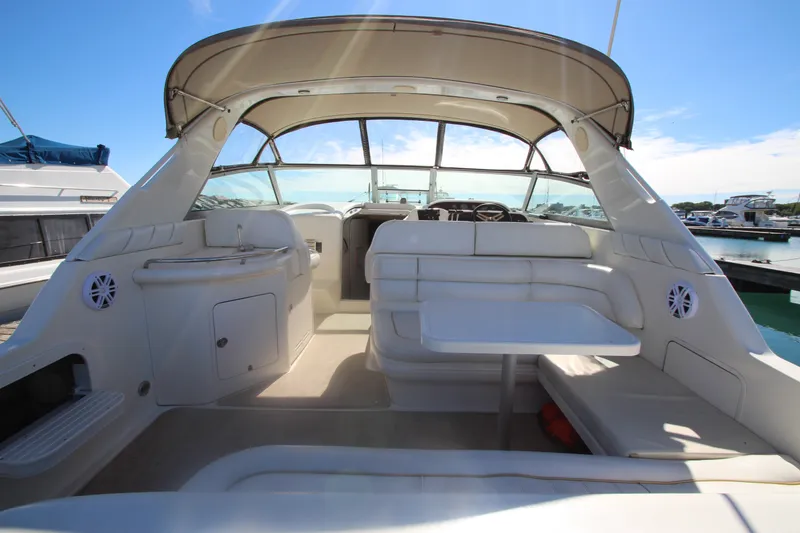 Slide: The Image of 1996 Sea Ray Sundancer 330 interior with seating and table, docked at marina under clear sky. - 5