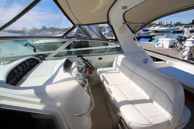 Slide: The Image of 1996 Sea Ray Sundancer 330 cockpit with white seating and helm, docked at marina. - 17