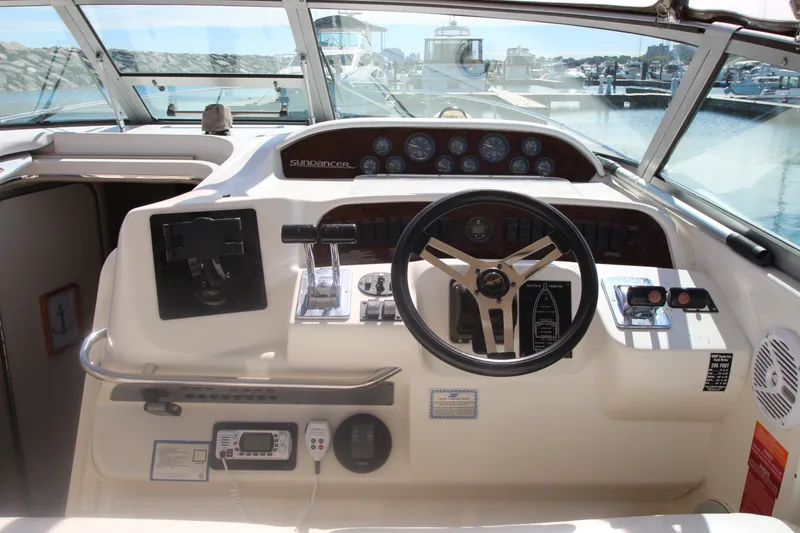 Slide: The Image of 1996 Sea Ray Sundancer 330 helm with steering wheel, controls, and gauges in a marina setting. - 14