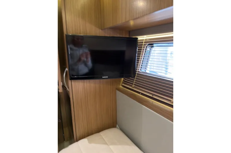 Slide: The Image of 2018 Sea Ray L590 interior with wall-mounted TV and window blinds. - 19