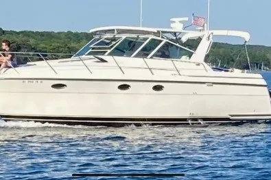 The Image of 1997 Tiara 3500 EXPRESS yacht cruising on a sunny day with lush greenery in the background. - 0