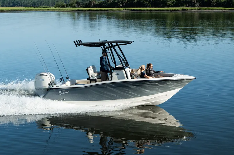 Slide: The Image of A Scout 200 Sportfish boat speeds across calm water with three people on board. - 2