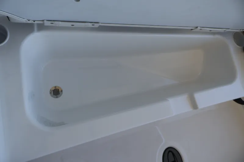 Slide: The Image of 2027 Tahoe T18 boat storage compartment with drain plug, white interior. - 27