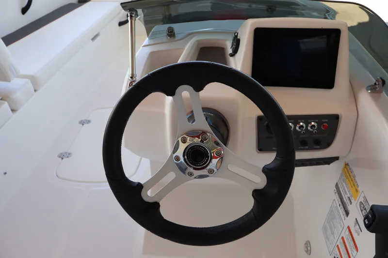 Slide: The Image of Steering wheel and dashboard of 2027 Tahoe T18 boat, featuring modern controls and display. - 16