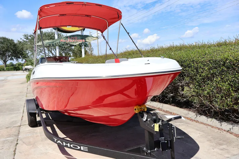 Slide: The Image of Red 2027 Tahoe T18 boat on trailer with canopy, parked outdoors under blue sky. - 6