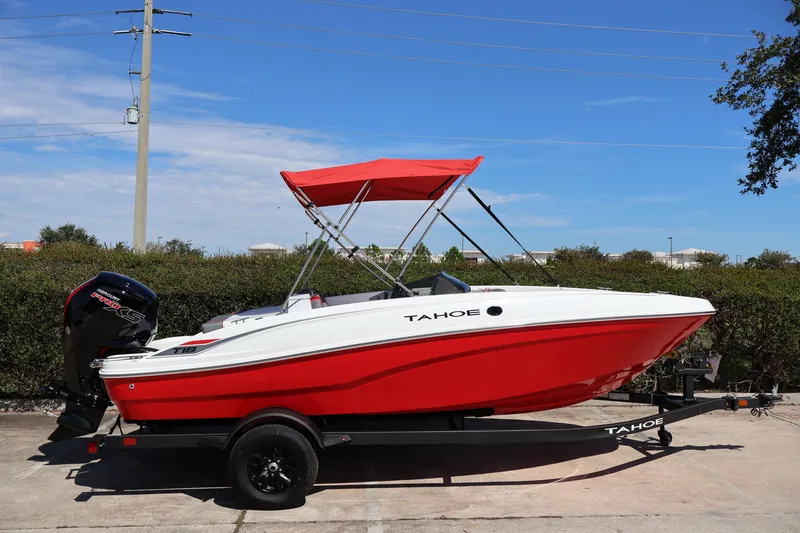 Slide: The Image of 2027 Tahoe T18 boat with red hull and canopy on trailer, parked outdoors. - 4