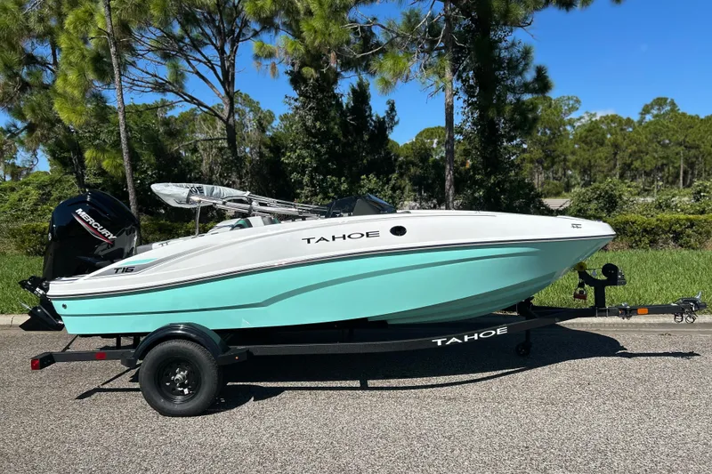 The Image of 2027 Tahoe T16 boat on trailer, parked on a sunny road with trees in background. - 0