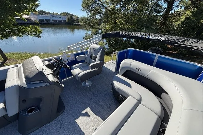 Slide: The Image of 2027 Sun Tracker Party Barge 18 DLX pontoon boat interior with plush seating by a serene lake. - 19