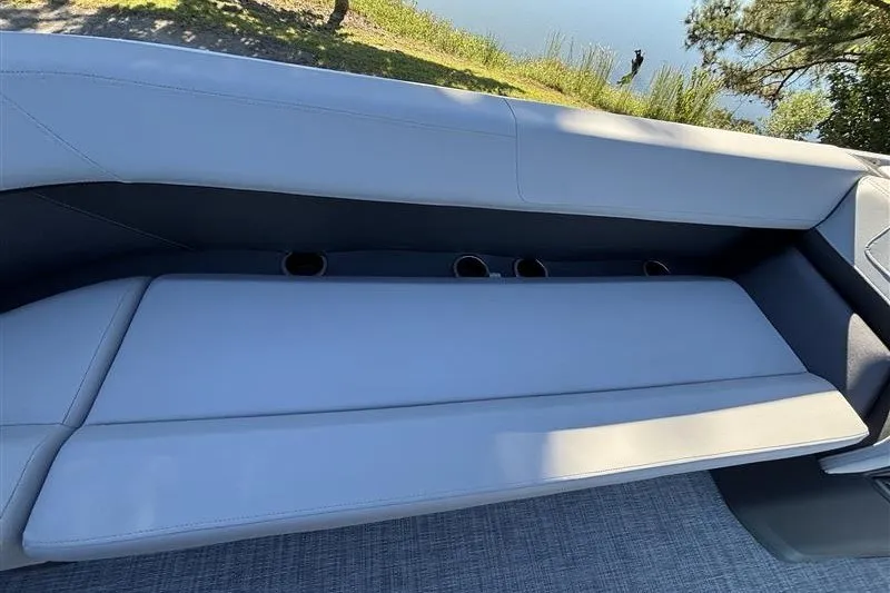 Slide: The Image of 2027 Sun Tracker Party Barge 18 DLX interior seating with cup holders, near water. - 13