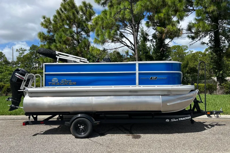 The Image of 2027 Sun Tracker Party Barge 16 DLX pontoon boat on trailer, parked roadside. - 0
