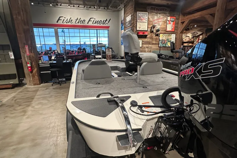 Slide: The Image of 2027 Tracker Savage 215 boat displayed indoors with Mercury Pro XS engine. - 14