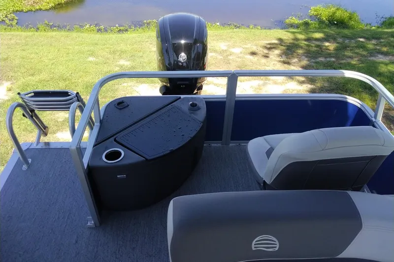 Slide: The Image of 2027 Sun Tracker Bass Buggy 18 DLX pontoon boat interior with seating and motor view. - 13