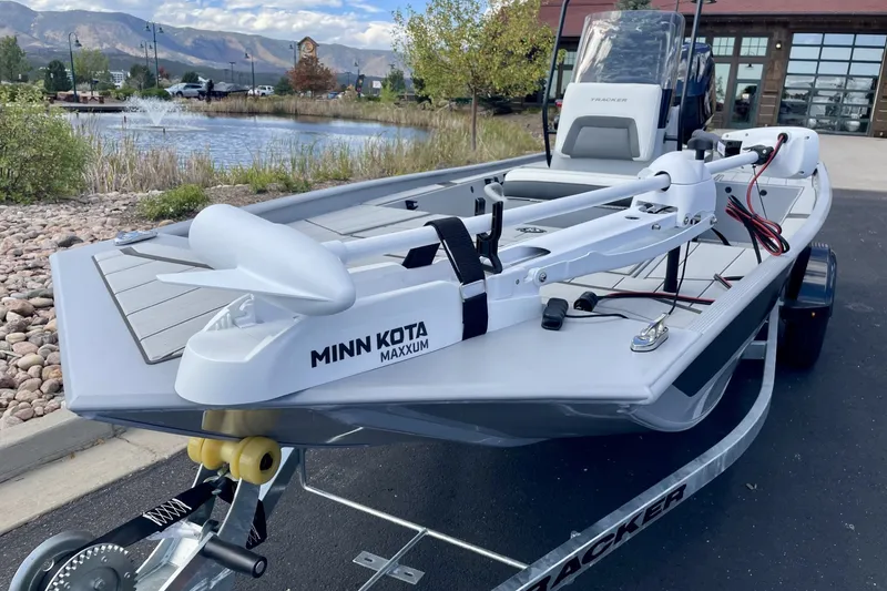 Slide: The Image of 2027 Tracker Bass Tracker Classic CC boat with Minn Kota Maxxum motor, parked near a scenic pond. - 13