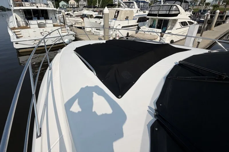 Slide: The Image of 2004 Neptunus 56 Flybridge yacht docked at marina, featuring sleek design and black covers. - 64