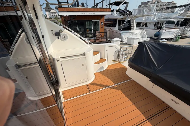 Slide: The Image of 2004 Neptunus 56 Flybridge yacht deck with teak flooring and covered seating area. - 8