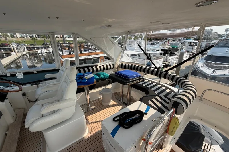Slide: The Image of Luxurious 2004 Neptunus 56 Flybridge yacht interior with white seating and marina view. - 12