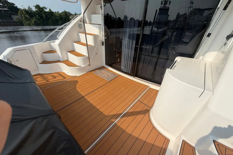 Slide: The Image of 2004 Neptunus 56 Flybridge yacht deck with wooden flooring and staircase by the water. - 6