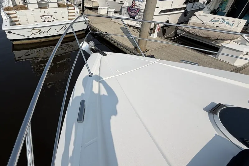 Slide: The Image of 2004 Neptunus 56 Flybridge yacht docked, featuring sleek white deck and marina surroundings. - 65
