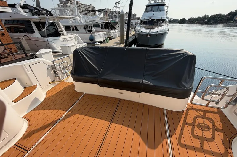 Slide: The Image of Luxurious 2004 Neptunus 56 Flybridge yacht docked, featuring sleek teak deck and covered seating. - 7
