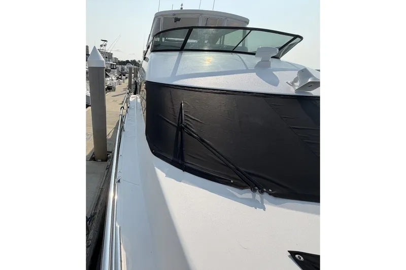 Slide: The Image of 2004 Neptunus 56 Flybridge yacht docked, featuring sleek design and black windshield cover. - 68