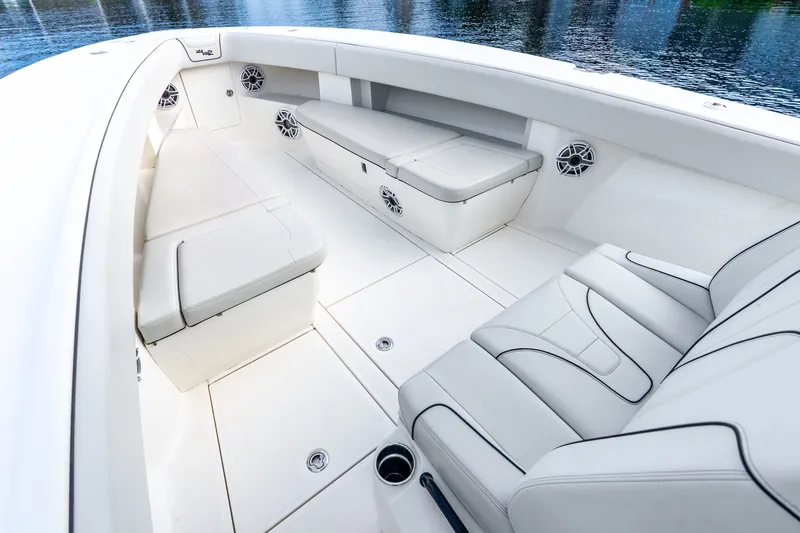 Slide: The Image of 2023 SeaVee 370Z boat interior with white seating and speakers, docked on calm water. - 30