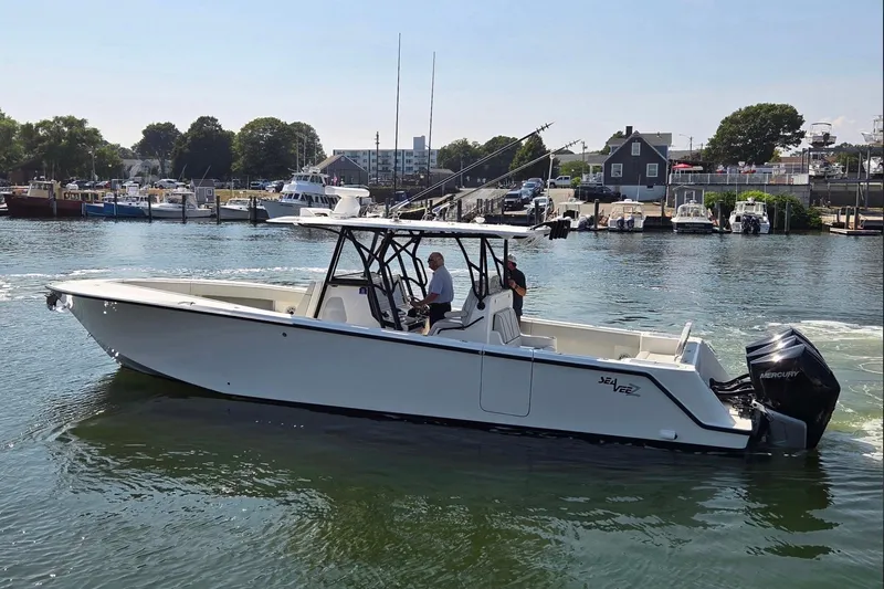 The Image of 2023 SeaVee 370Z boat cruising in a marina with Mercury outboard engines. - 1