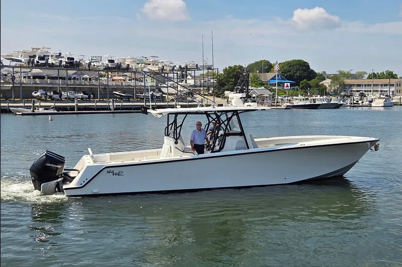 Slide: The Image of 2023 SeaVee 370Z boat cruising in a marina with docks and boats in the background. - 2