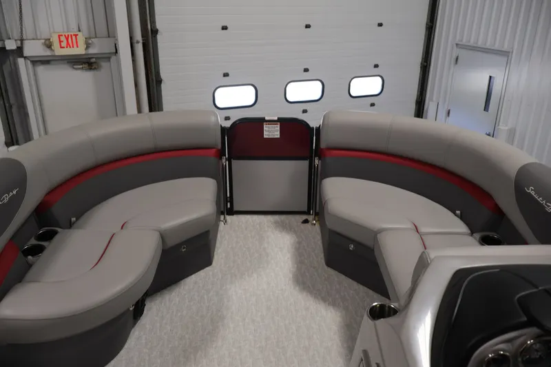 Slide: The Image of 2023 South Bay S222RS pontoon boat interior with gray and red seating in a garage. - 9