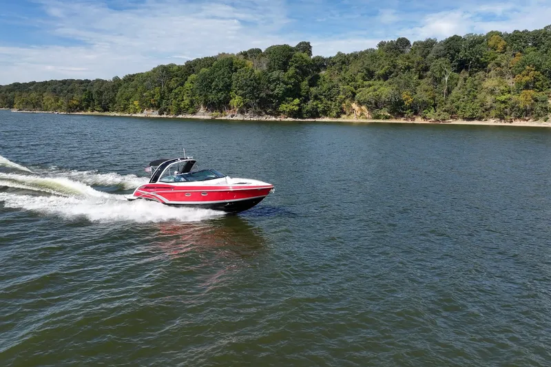 Slide: The Image of 2016 Formula 330 Crossover Bowrider cruising on a scenic lake with lush green shoreline. - 14
