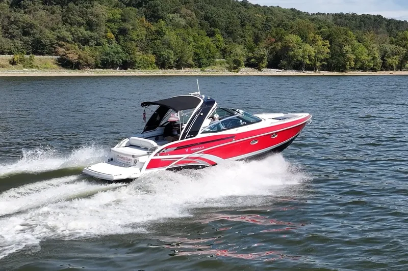 Slide: The Image of 2016 Formula 330 Crossover Bowrider cruising on a lake with lush green shoreline. - 15