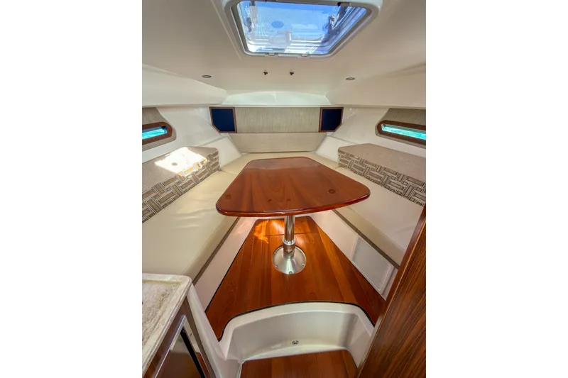 Slide: The Image of 2023 Pursuit OS 325 Offshore cabin interior with wooden table and seating. - 10