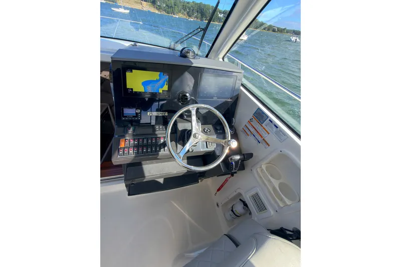 Slide: The Image of Helm of 2023 Pursuit OS 325 Offshore boat with navigation display and steering wheel. - 7