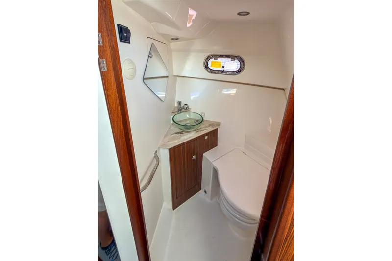 Slide: The Image of 2023 Pursuit OS 325 Offshore boat bathroom with modern sink and wooden cabinetry. - 13