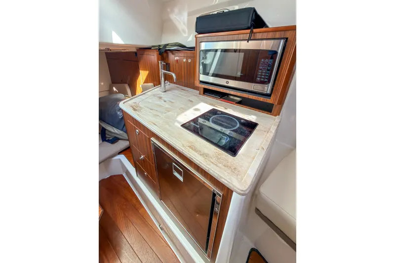 Slide: The Image of 2023 Pursuit OS 325 Offshore boat kitchen with microwave, sink, and cooktop. - 12