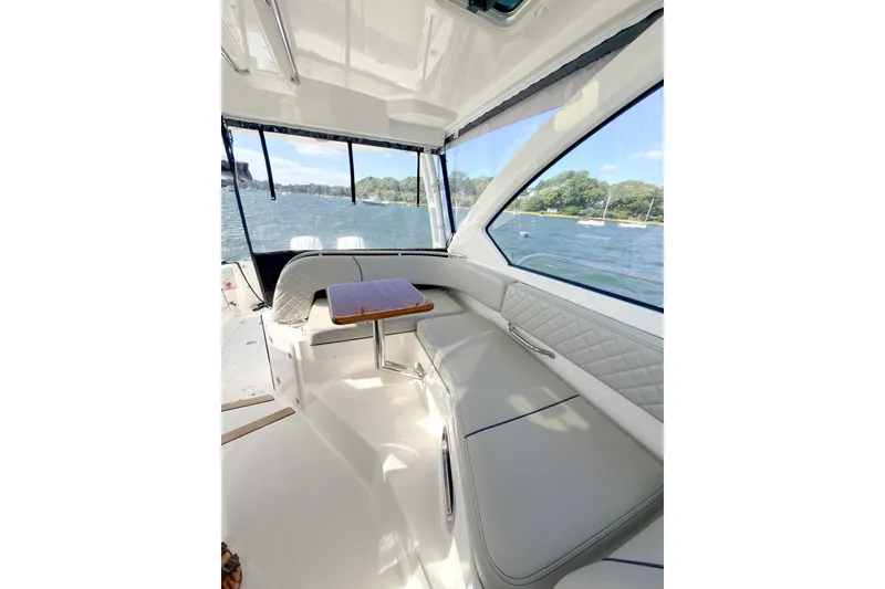 Slide: The Image of 2023 Pursuit OS 325 Offshore boat interior with seating and table, overlooking scenic water view. - 9
