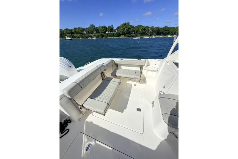 Slide: The Image of 2023 Pursuit OS 325 Offshore boat interior with cushioned seating, docked on a sunny day. - 5