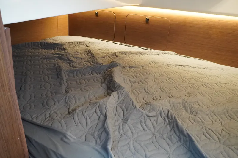 Slide: The Image of 2024 Jeanneau NC Sport 895 cabin with quilted bedding and wooden accents. - 33