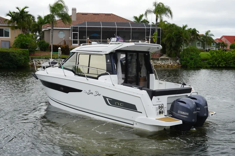 Slide: The Image of 2024 Jeanneau NC Sport 895 boat with twin Yamaha engines on a scenic waterway. - 3