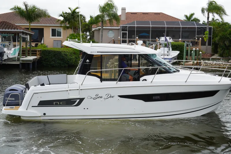 Slide: The Image of 2024 Jeanneau NC Sport 895 boat cruising near waterfront homes. - 6