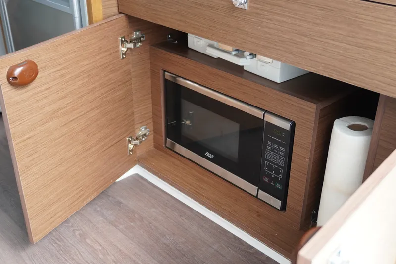 Slide: The Image of 2024 Jeanneau NC Sport 895 interior with built-in microwave and storage cabinet. - 16